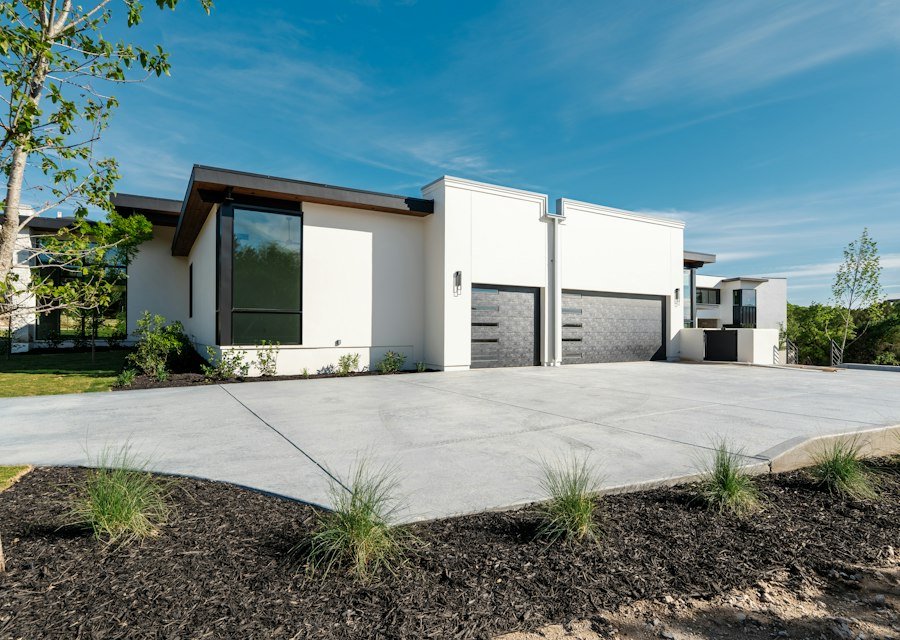 Modern white house, two garage doors, and concrete driveway
