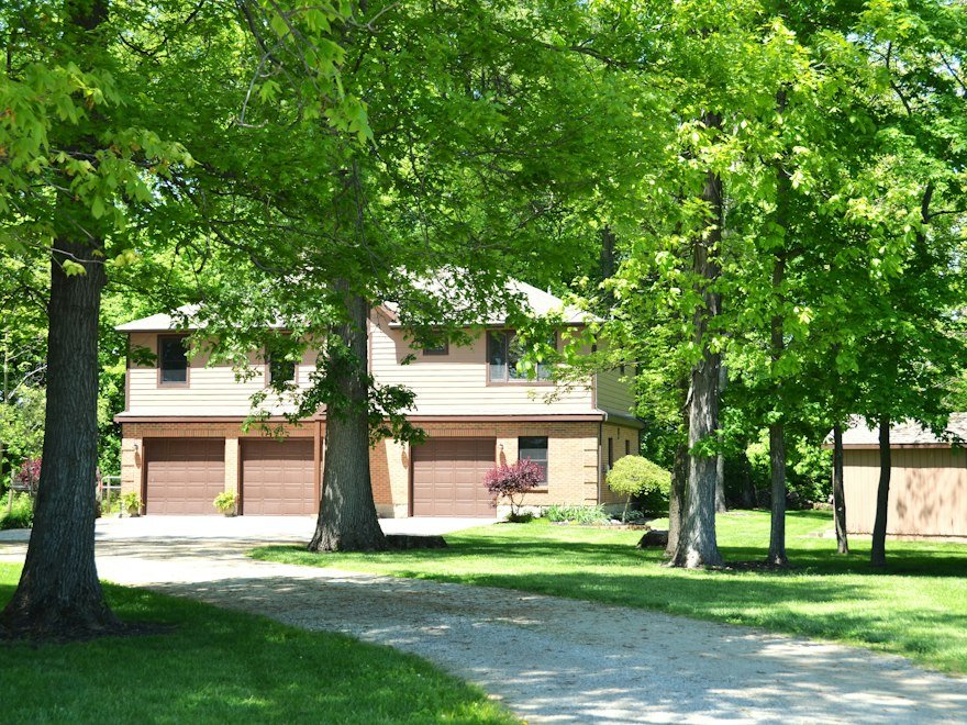 House with three garage doors surrounded by trees