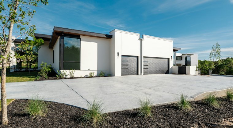 Modern white house, two garage doors, and concrete driveway