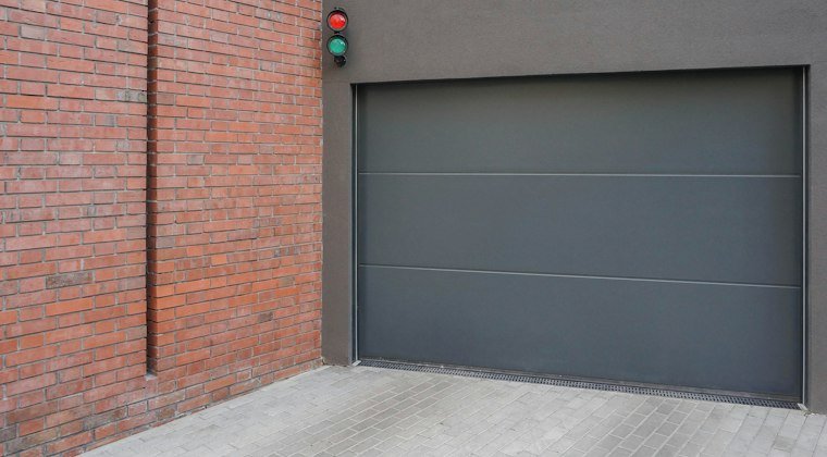 Grey garage door next to a brick wall